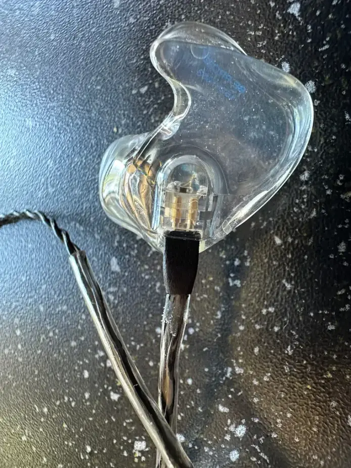 A clear acrylic Big Ear custom IEM showing the driver and connector
