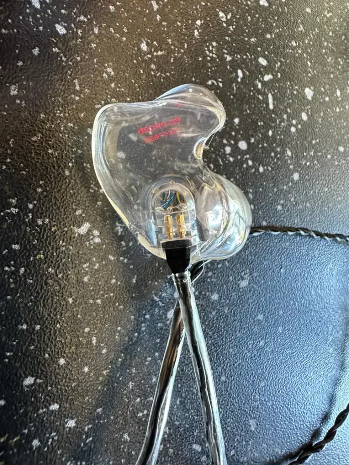 A clear acrylic Big Ear custom IEM with a detachable two-pin cable