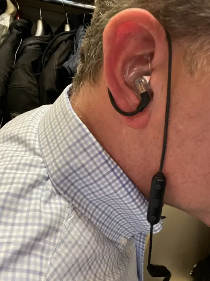 A customer wearing a clear acrylic custom IEM with an over-ear hook