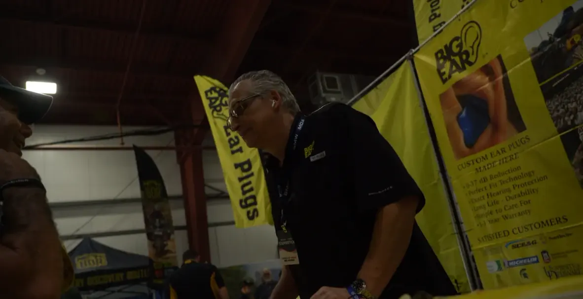 Two people smiling together at the Big Ear booth